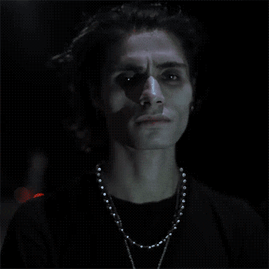 a man with dreadlocks is wearing a black shirt and a silver necklace
