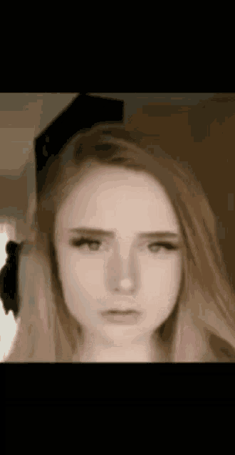 a close up of a woman 's face with long blonde hair and a serious look on her face .