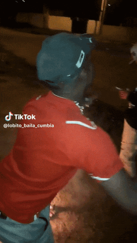 a man wearing a red shirt and a blue hat is dancing in a video that says tiktok
