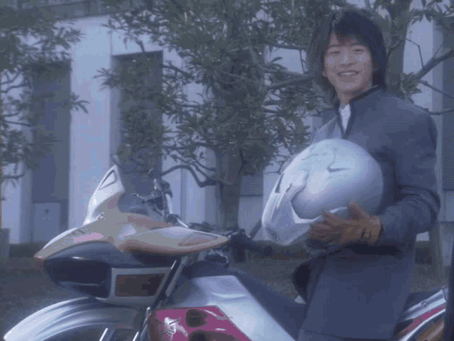 a man in a suit holds a white helmet in front of a motorcycle with a red tail