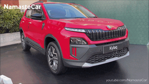 a red skoda kylaq is displayed in front of a green wall