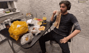a man wearing headphones sits at a table with a bag of chips on it