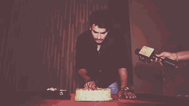 a man is cutting a cake in front of a microphone that says ' nbc ' on it