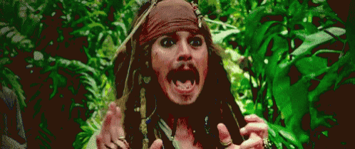 a man with dreadlocks and a bandana on his head is standing in the jungle with his mouth open .