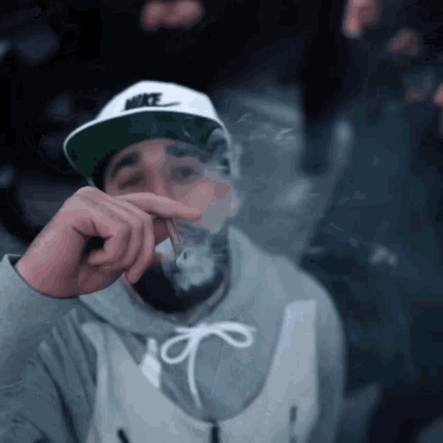 a man wearing a nike hat is smoking a joint