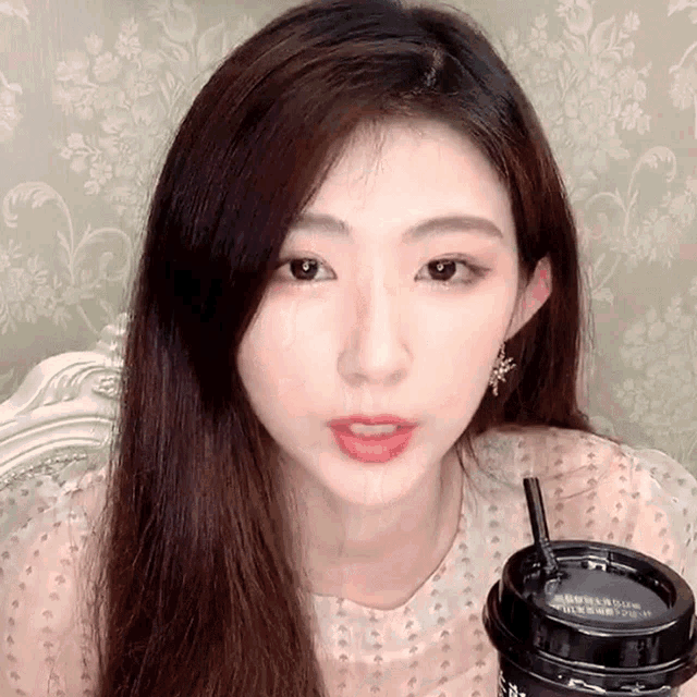 a woman holding a cup with a straw that says ' strawberry ' on it