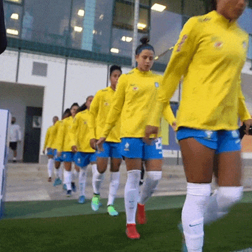 a group of female soccer players wearing yellow shirts and blue shorts