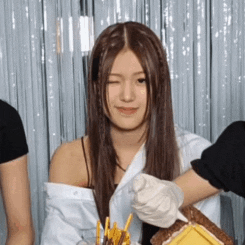 a woman with long hair is smiling while holding a gingerbread house
