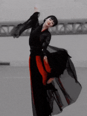a woman in a black and red dress is dancing in a room .