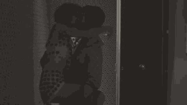 a man and woman kissing in front of a wall with a pattern