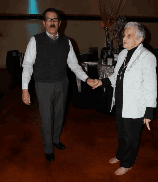 a man and a woman are holding hands and dancing on a dance floor