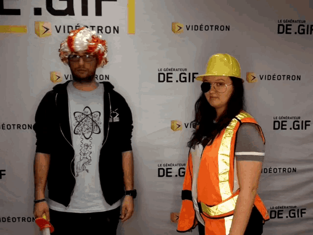 a man in a wig and a woman in an orange vest pose for a photo in front of a wall that says de.gif