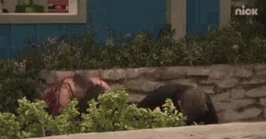 a woman is laying on the ground in front of a blue house .
