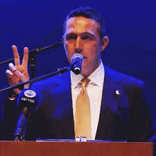 a man in a suit and tie is giving a peace sign while standing at a podium .