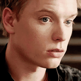 a close up of a young man 's face with blue eyes and a serious look on his face .