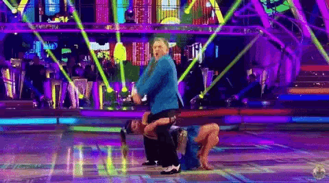 a man in a blue suit is dancing with a woman on a stage .