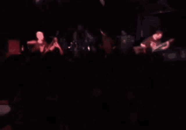 a blurry picture of a man playing a guitar in a band .