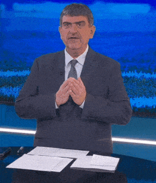 a man in a suit and tie stands in front of a blue background with the words a pezzente a miserabile