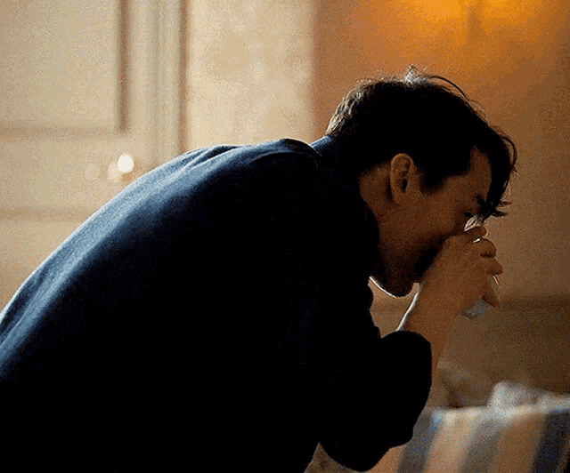 a man in a black sweater is holding his hand to his face