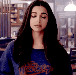 a woman with her eyes closed is wearing a blue t-shirt with the word new york on it .