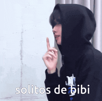 a person wearing a black hoodie has their finger on their lips and the words solitos de bibi above them