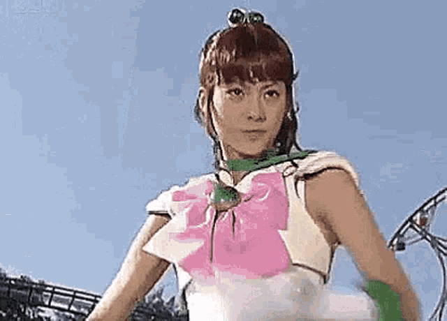a woman in a sailor moon costume is standing in front of a roller coaster and looking at the camera .