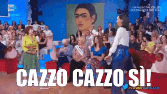 a woman is standing in front of a crowd with the words cazzo cazzo si
