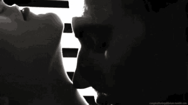 a man and a woman are kissing in front of a piano keyboard .