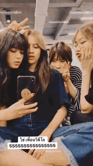 a group of girls are posing for a picture and one of them is looking at her phone