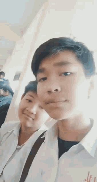 two boys are posing for a picture and one of them has a letter l on his shirt