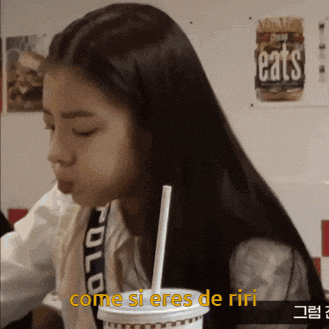 a girl drinking from a cup with a straw and the words come si eres de riri above her