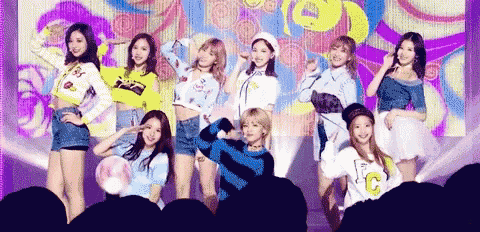 a group of girls are posing for a picture on a stage . one of the girls is wearing a shirt with the letter c on it