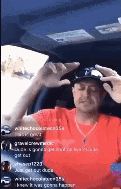 a man in a red shirt is sitting in a car with a hat on