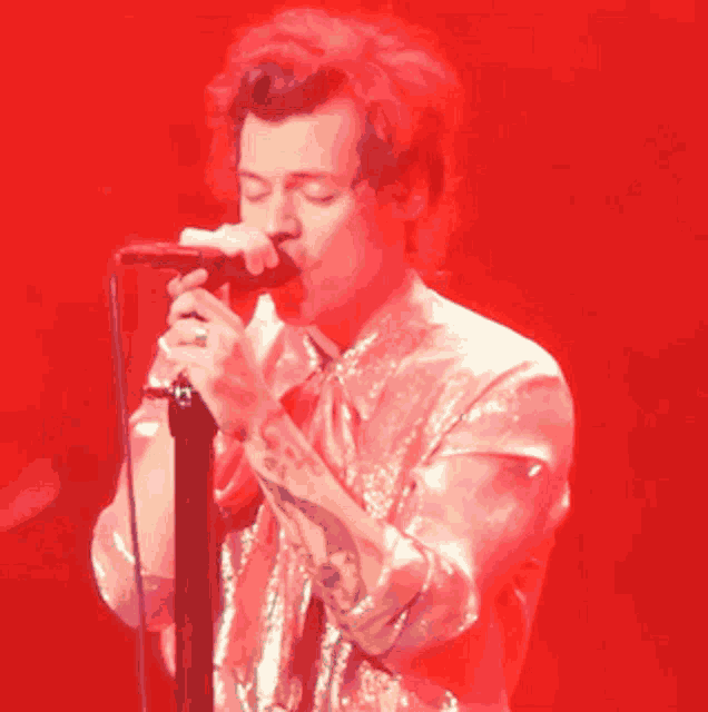 a man is singing into a microphone in front of a red background