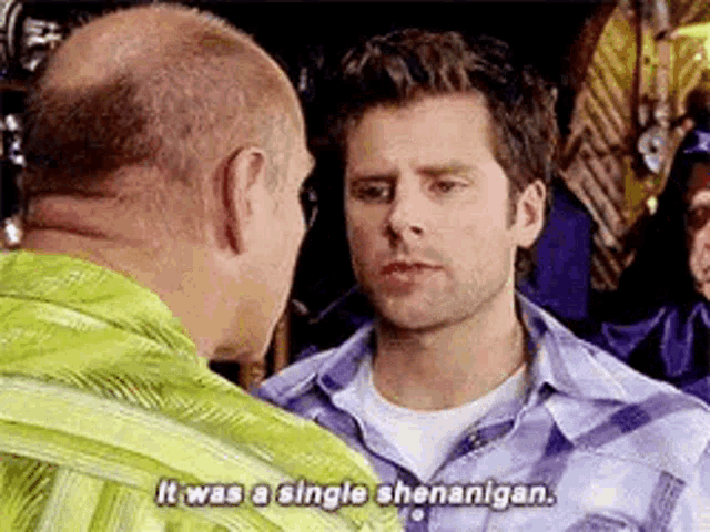 two men are standing next to each other and talking to each other .
