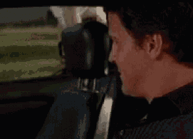 a man is sitting in the driver 's seat of a car looking out the window .