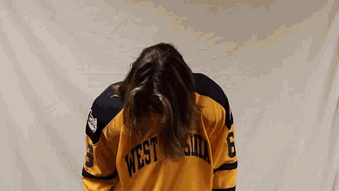 a woman wearing a yellow west virginia jersey is dancing