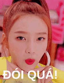 a close up of a woman 's face with a ponytail and a yellow shirt with the words doi qua written on it .