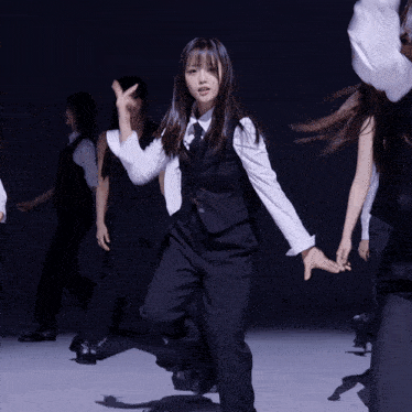 a group of people in suits and white shirts are dancing in a dark room
