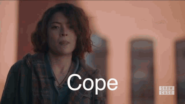 a woman in a plaid jacket is standing in front of a building with the word cope written on her face .