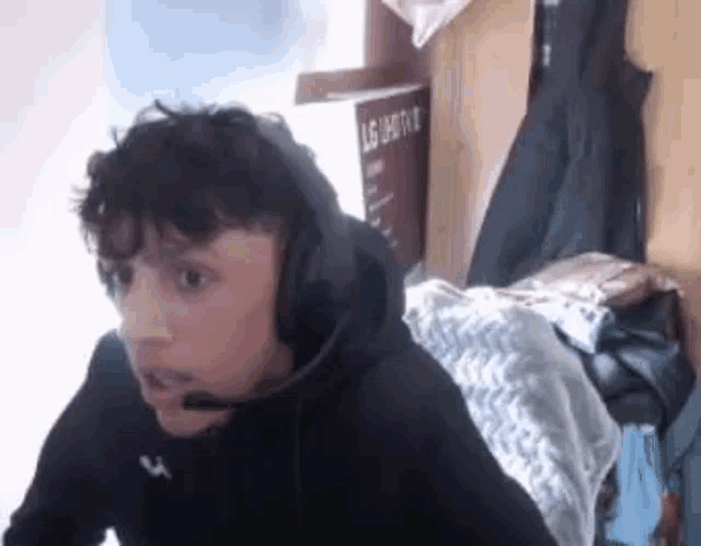 a man wearing headphones and a microphone is sitting in a room .