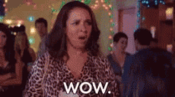 a woman in a leopard print shirt is standing in a crowd of people and says wow .
