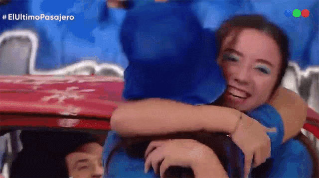 a woman is hugging another woman in front of a sign that says el ultimo pasajero