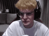 a man wearing glasses and headphones is sitting in front of a computer screen .