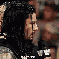 a man with long hair is talking into a microphone while wearing headphones .