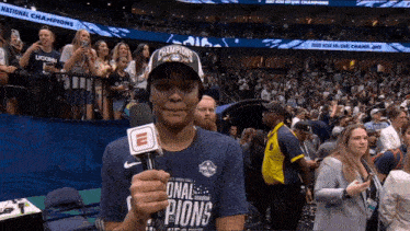 a woman holding a microphone in front of a crowd that says national champions