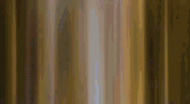 a cartoon character is standing in front of a curtain with a red light coming out of it .