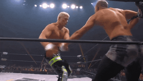 two men are fighting in a wrestling ring and one of them is wearing shorts with the word aew on them