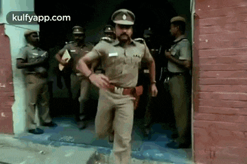 a police officer is running out of a building with other police officers standing behind him .