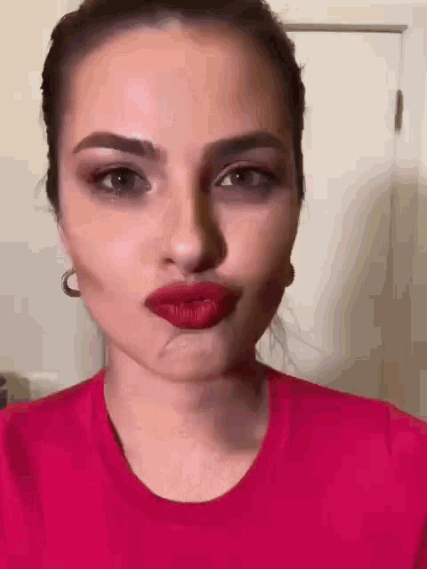 a woman in a red shirt is making a funny face with her mouth open .